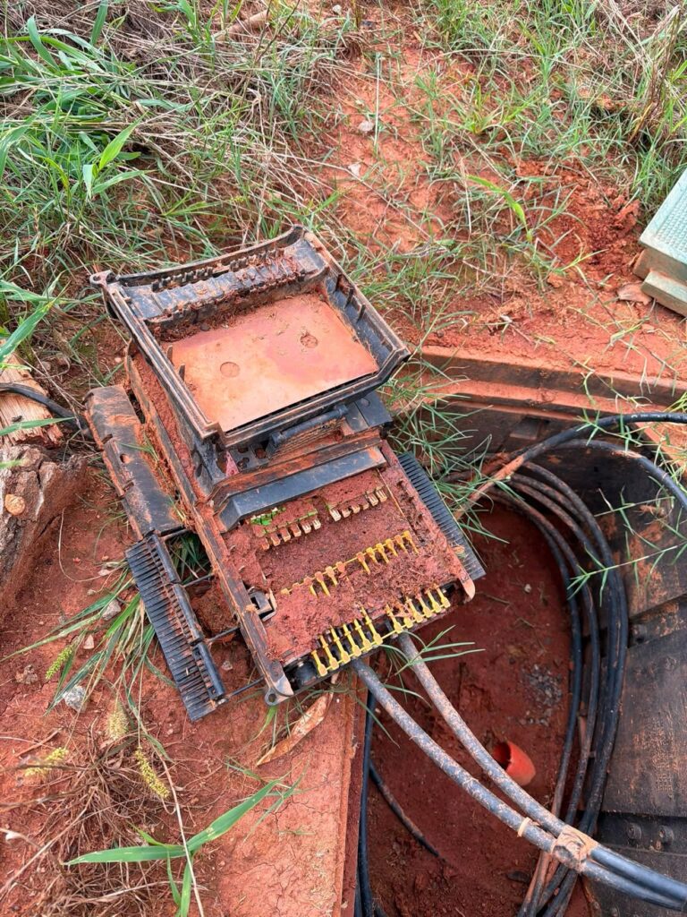 Fiber terminal pulled from a handhole and opened, its ports packed with red mud.